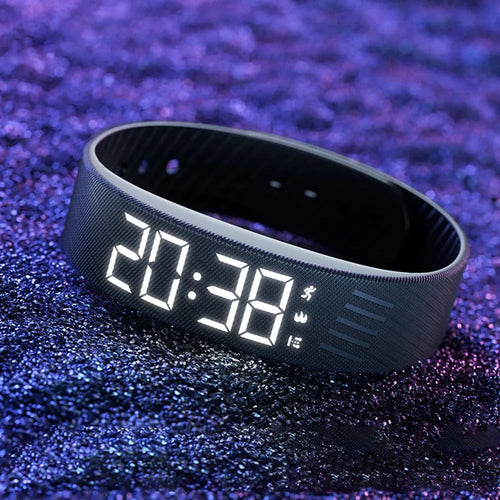 WristWake silent vibrating alarm band in black, glowing LED time display at night
